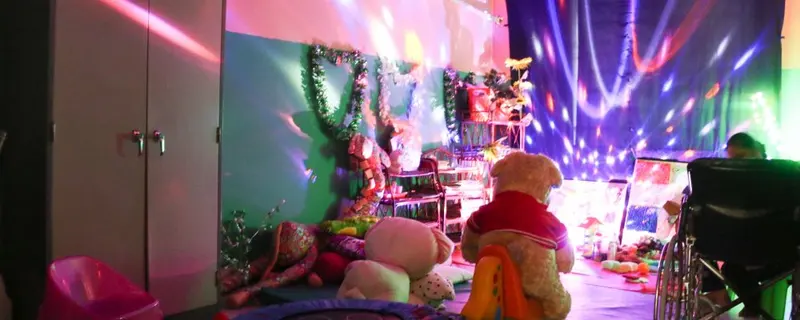 A sensory room glowing with colored lights and soft toys.